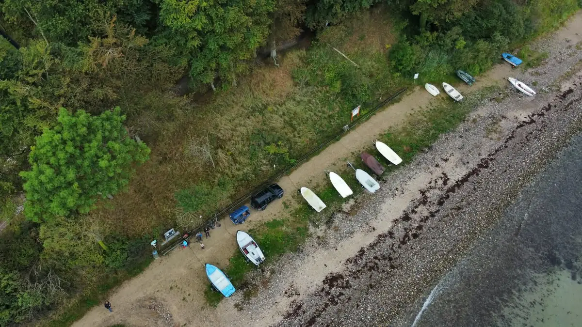 Luftbild: Kleinboote aufgereiht am Strandweg unter dem Buchenwald