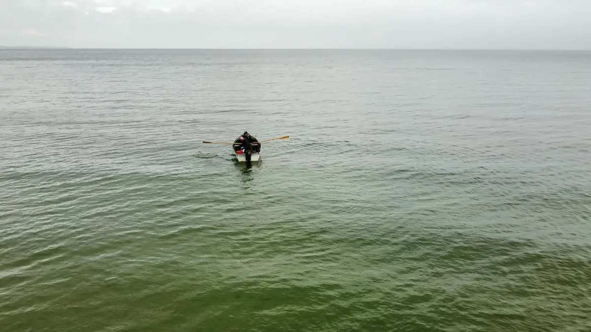 Angler rudert mit seinem Boot hinaus aufs Wasser