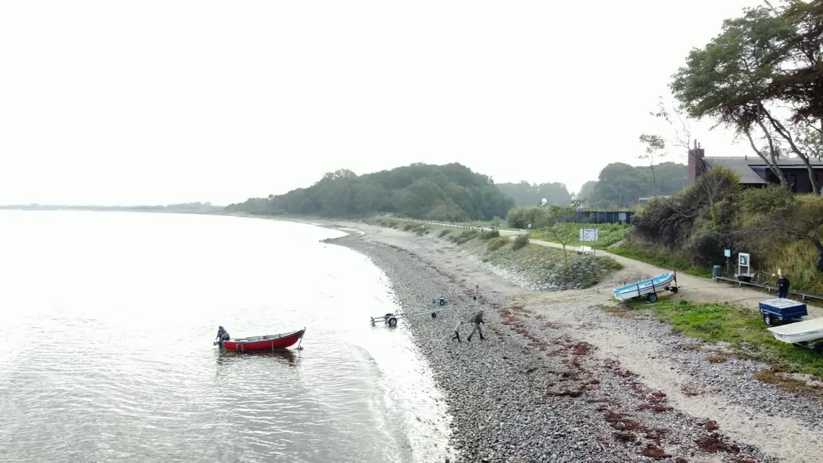 Rotes Boot an der Wasserkante, Mitglieder am Strand